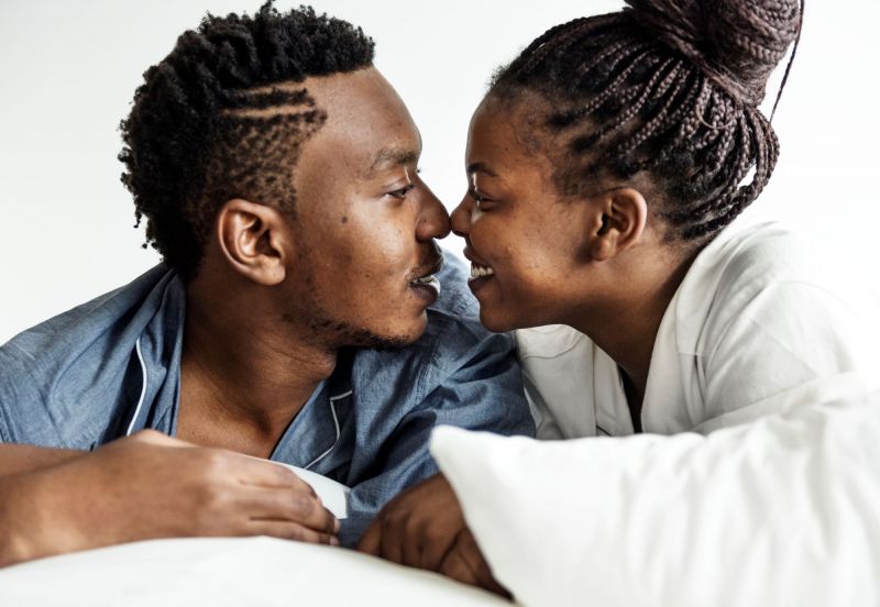 Couple souriant touchant le nez au lit