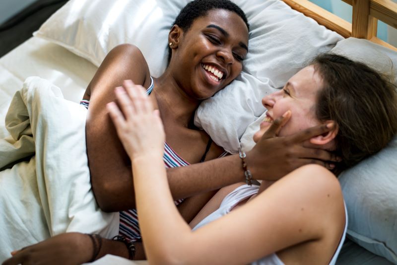 Happy lesbian couple laughing in bed