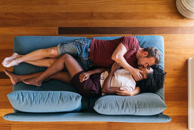 Happy lovers resting and kissing on sofa