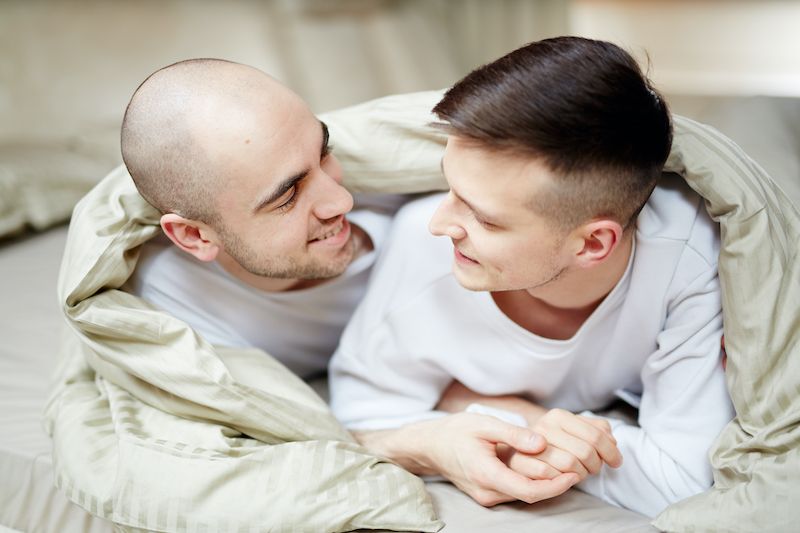 Happy loving couple at home wrapped in a duvet