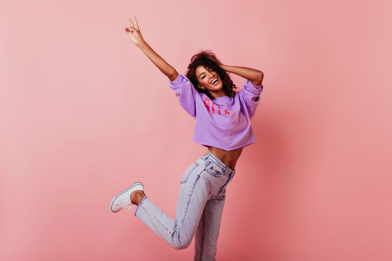 Happy woman jumping on pink background
