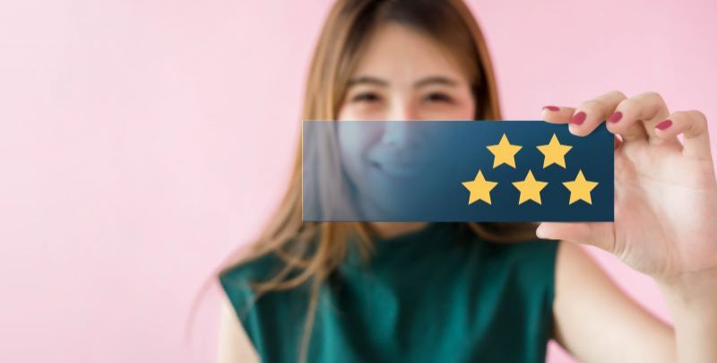 Happy woman holding up 5 stars