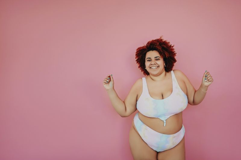 Smiling woman in bikini on pink background