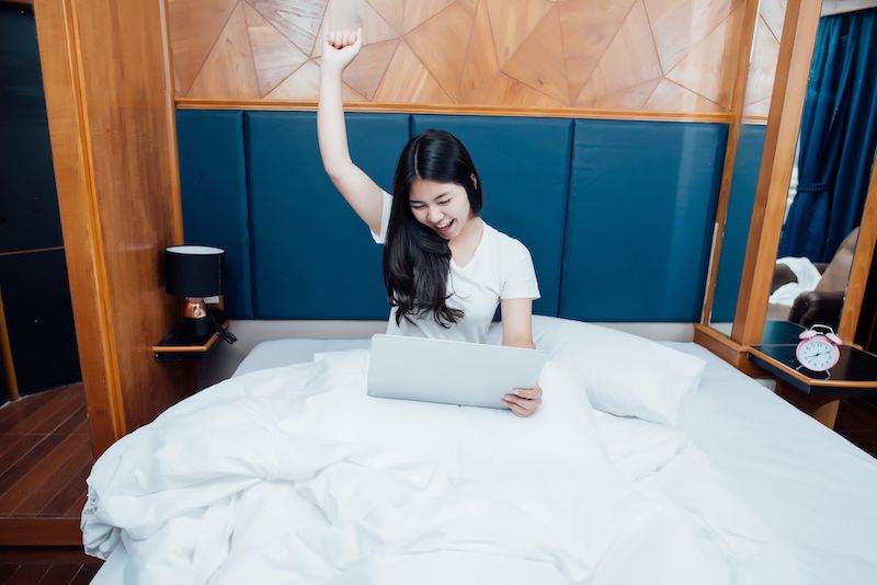 Femme célébrant sur son ordinateur portable au lit