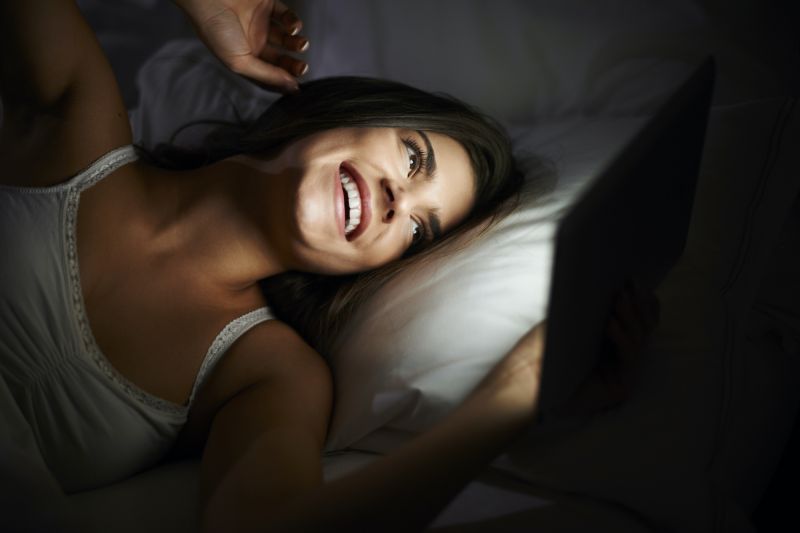 Femme heureuse au téléphone au lit la nuit