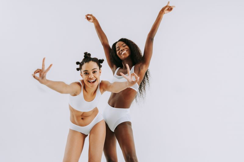Happy women posing and doing peace signs in underwear