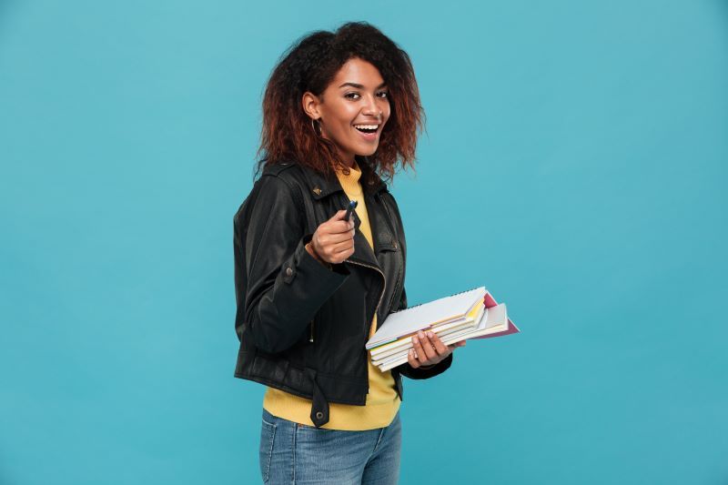 Happy young woman holding books