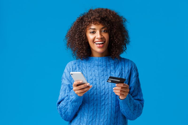 Mulher jovem e feliz a fazer um pagamento por telemóvel