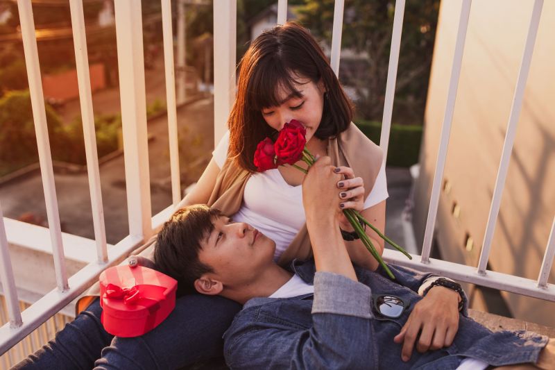 Lovers laying on balcony with red roses and red gift box