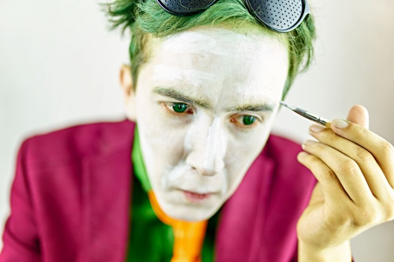 Male cosplayer putting on Joker make up