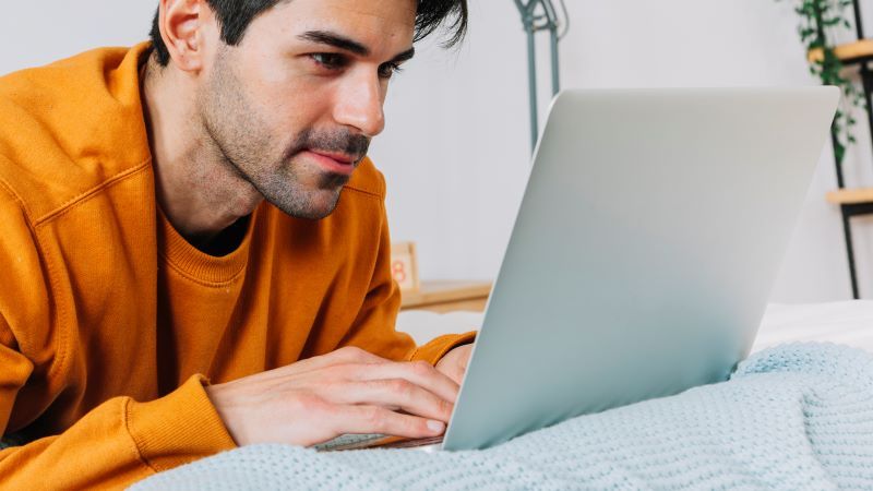 Homme utilisant un ordinateur portable au lit