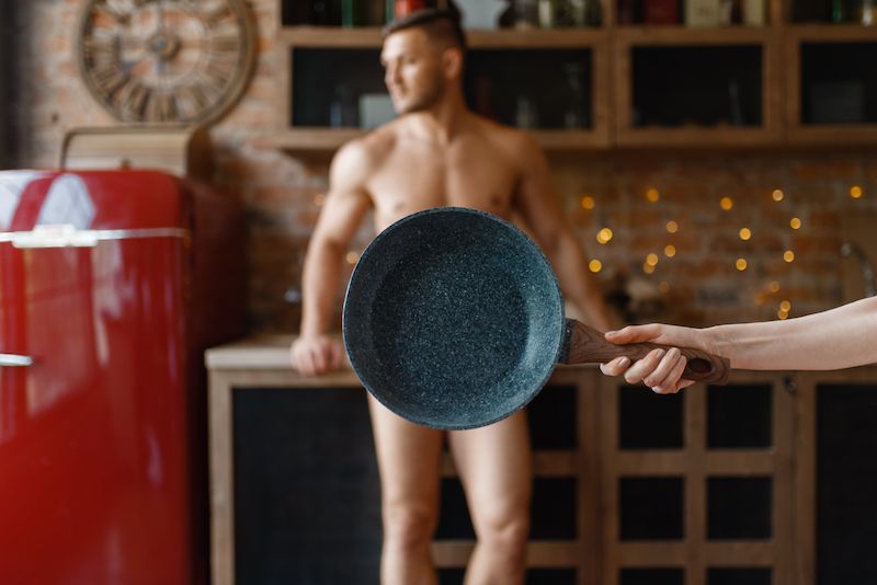 Homme nu dans la cuisine avec une casserole couvrant son entrejambe
