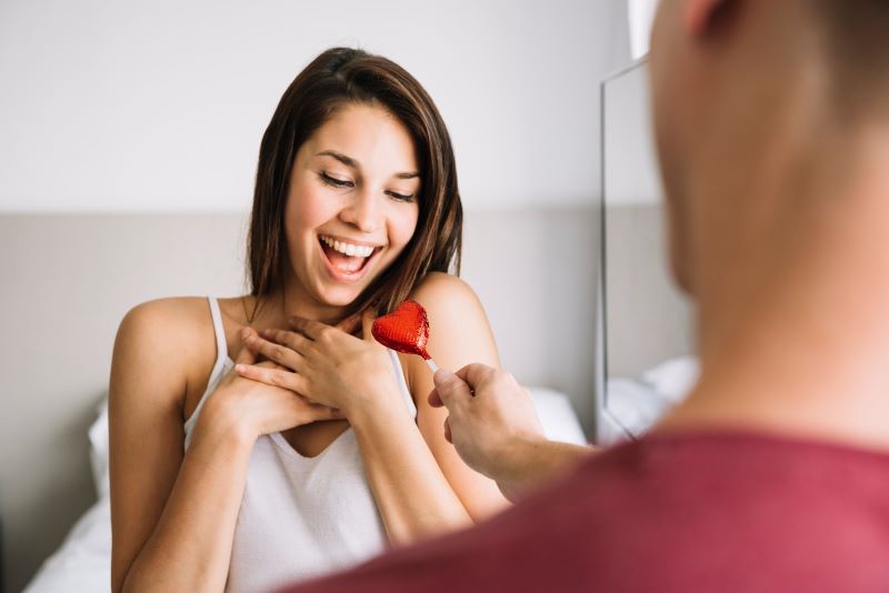 Man giving woman heart-shaped lollipop