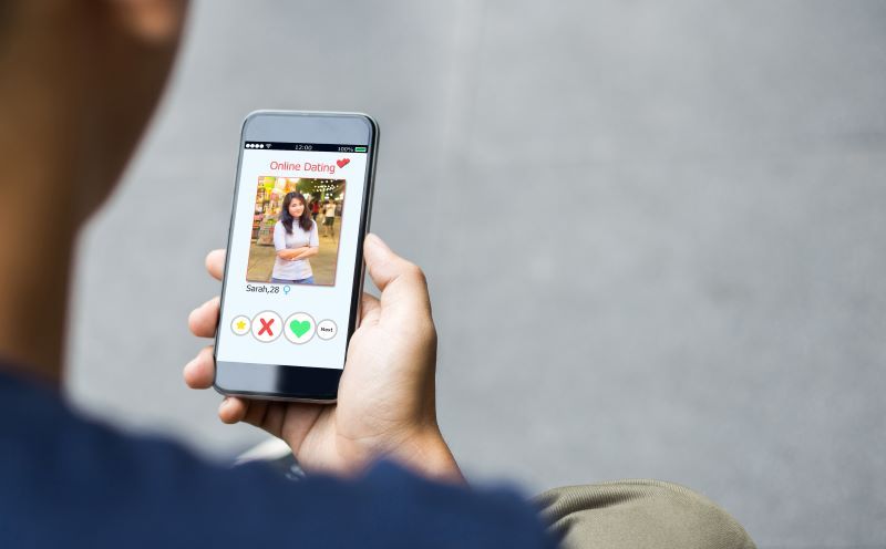 Man holding a phone screen showing a dating app