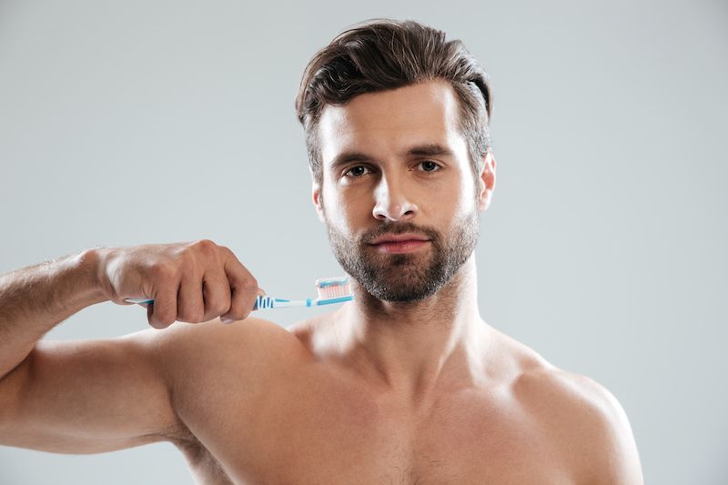 Man holding toothbrush to his face