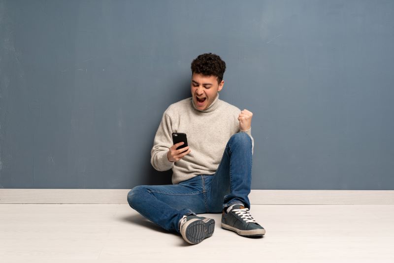 Man sitting phone celebrating