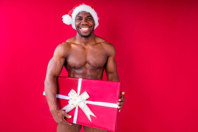 Homme nu en bonnet de noel tenant un cadeau