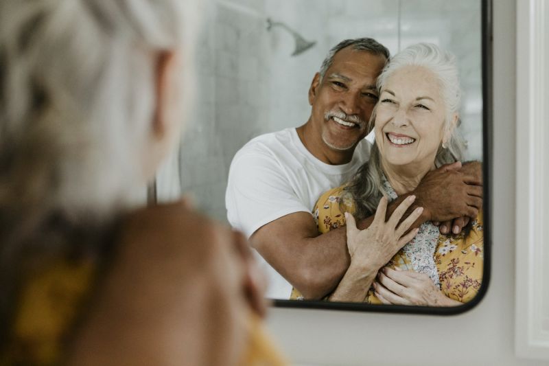 Older couple hugging and smiling in mirror