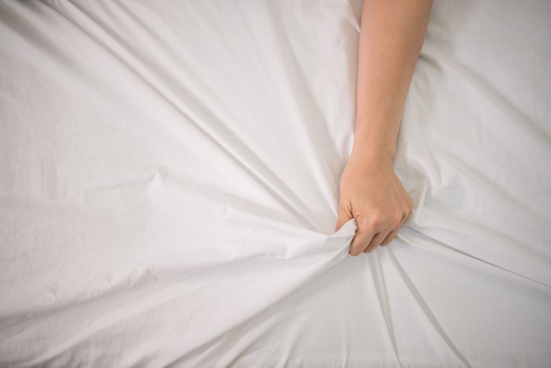 Hand grabbing sheets because of orgasm