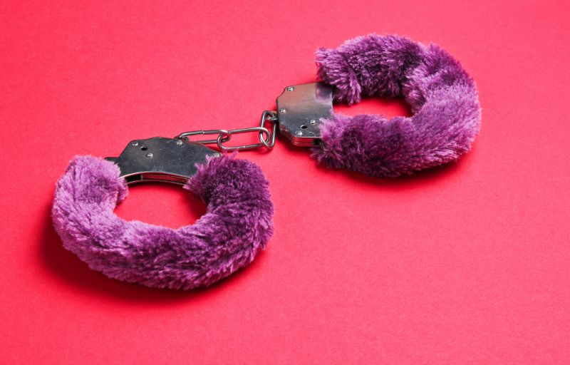 Purple fluffy handcuffs on red background