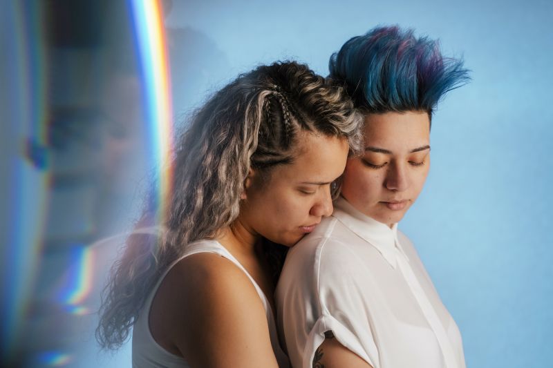 Queer couple hugging intimately in blue room