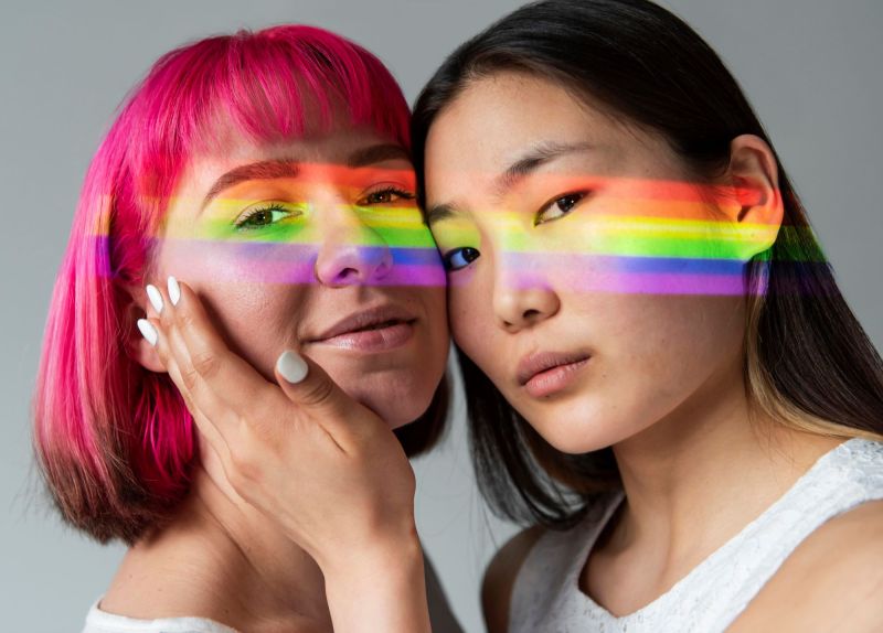 Queer couple touching faces with rainbow stripe