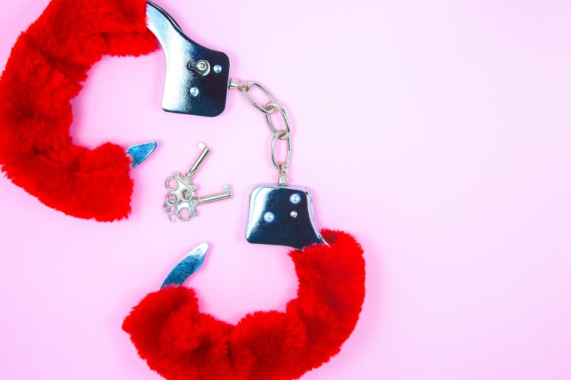 Red fluffy handcuffs on pink background