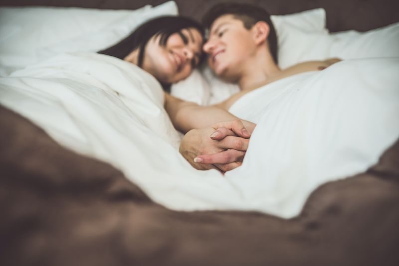 Romantic couple holding hands in bed