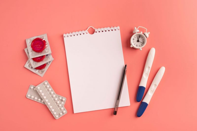 Sexual health kit and notepad on pink desk