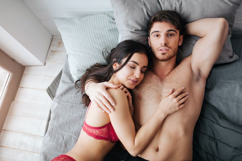Sexy satisfied couple cuddling in bed