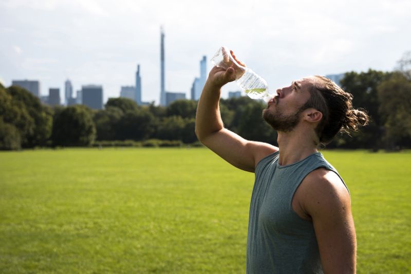 Side view male athlete drinking water outside