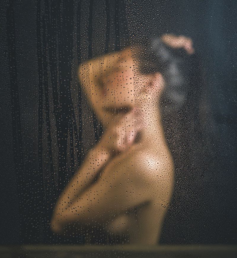 Side view nude woman behind steamy shower glass