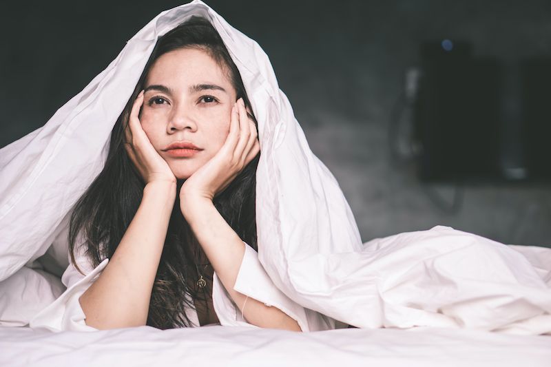 Sleepless woman in bed looking thoughtful