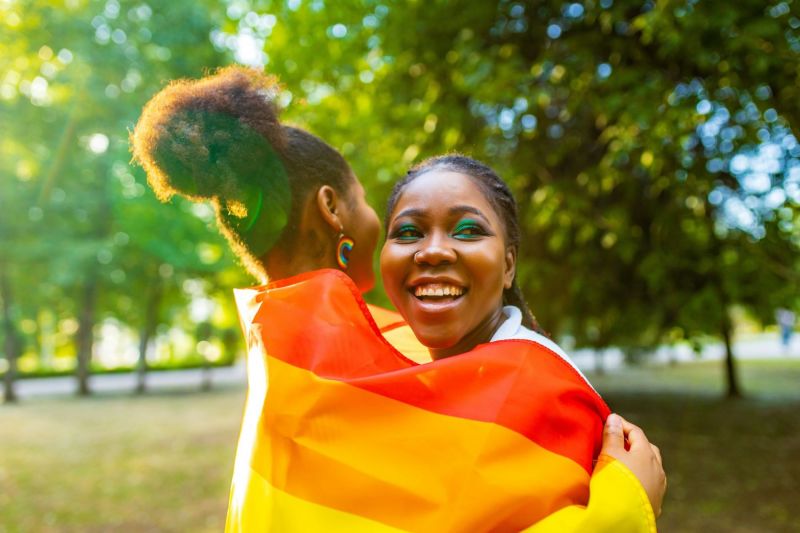 Couple souriant embrassant avec drapeau arc-en-ciel