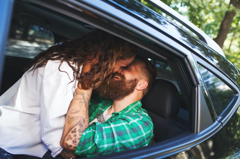 Couple souriant s'embrassant dans une voiture