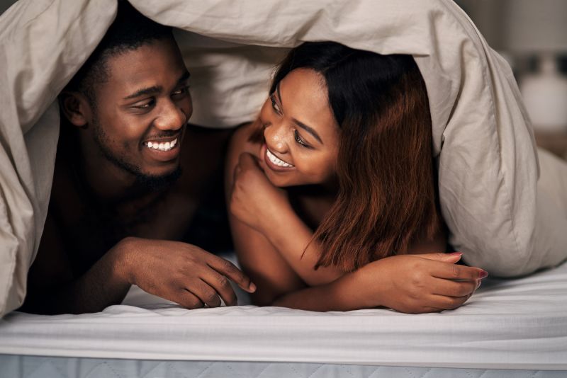 Smiling lovers in bed at home