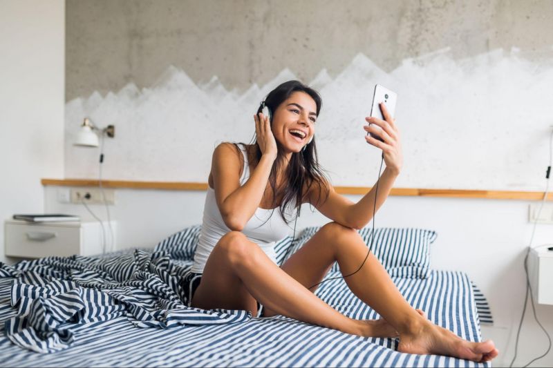 Femme souriante en appel vidéo sur le lit