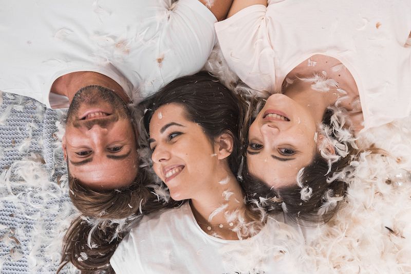 two women and one men in bed