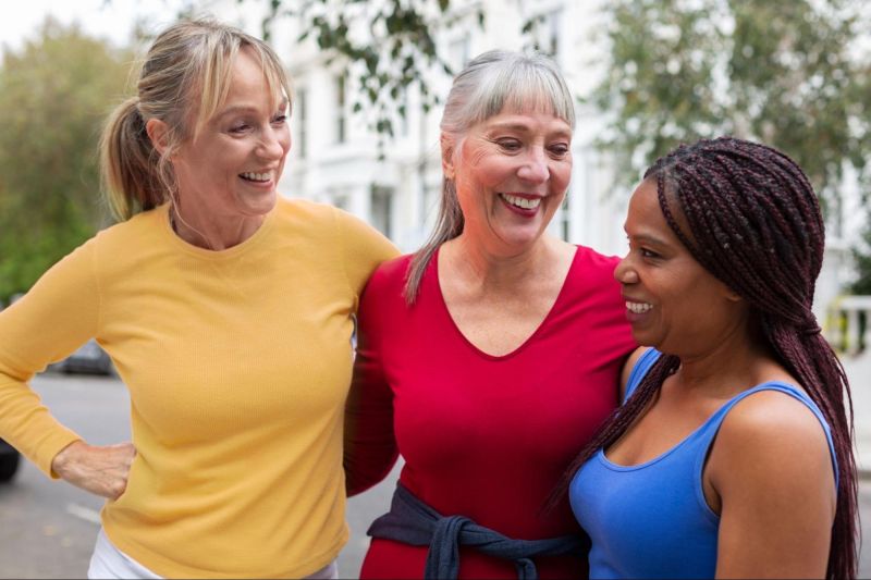 Trois femmes souriant à l'extérieur dans des vêtements de sport