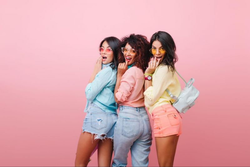 Three women posing on pink background