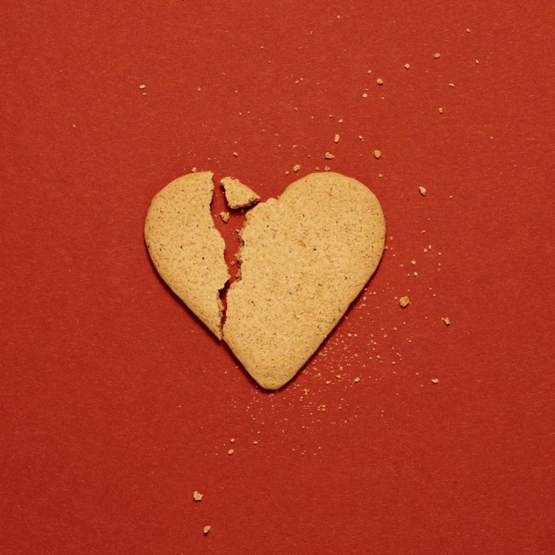 Broken heart shape biscuit on red background