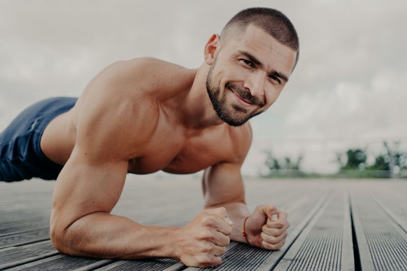 Topless man smiling while exercising