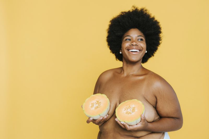 Topless smiling woman holding melon sur les seins