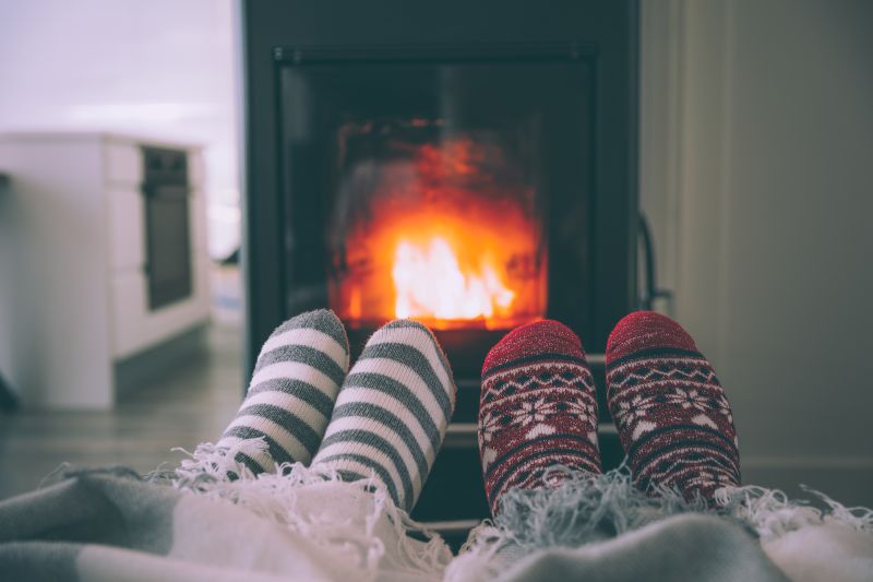 Two pairs of feet in winter socks with fireplace