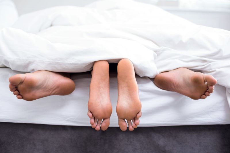 View of feet of couple having sex in bed