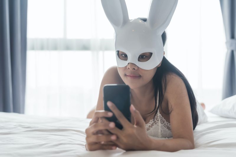 Woman taking selfie in bed in rabbit mask