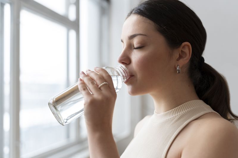 Woman drinking water at home after exercise
