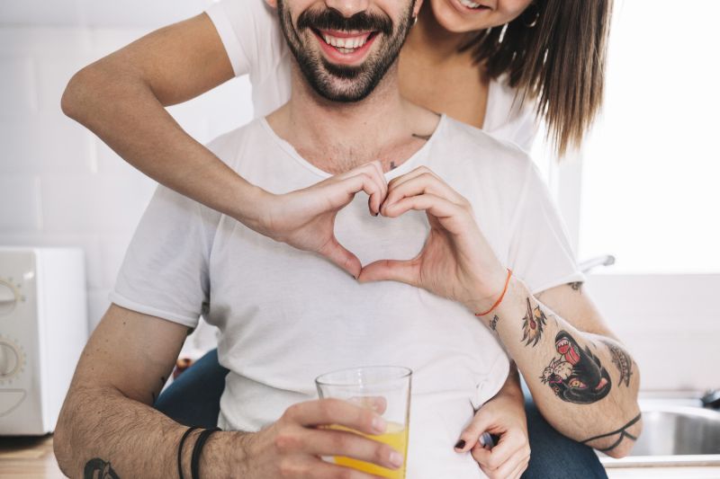 Woman embracing man from behind making heart hands