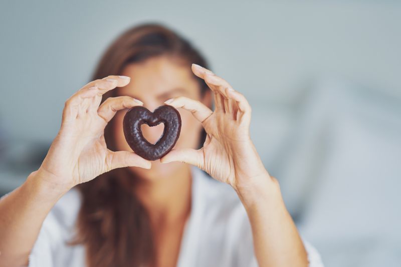 Femme tenant un biscuit au chocolat en forme de coeur