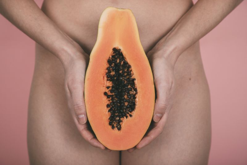 Femme tenant la papaye devant l'entrejambe des hanches